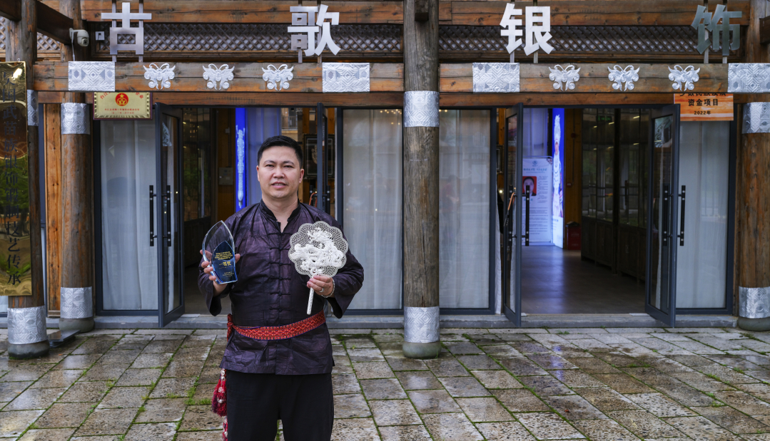 15.吳國武手持獲獎作品在銀飾店鋪前--尹剛--13985702512.jpg